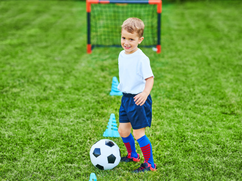 Little Boy practising soccer outdoors